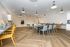 Modern community room featuring stylish wooden flooring, ample seating with colorful chairs, and elegant pendant lighting, perfect for gatherings and creative activities.
