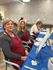 Cheerful painting session with creative individuals wearing red aprons, surrounded by art supplies and colorful canvases.