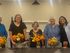 Joyful group standing behind a table adorned with vibrant autumn-themed floral arrangements, creating a warm and inviting atmosphere.