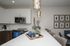 Modern kitchen with sleek white cabinets, stainless steel appliances, and elegant pendant lighting over a spacious island. Includes chic decor and cozy seating area.