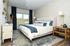 Modern bedroom with elegant design features a cozy bed, chic decor, large window view, and warm lighting.