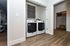 Modern laundry area in a stylish apartment featuring high-efficiency washer and dryer with elegant wood flooring.