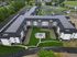 Aerial view of a modern, expansive apartment complex with a beautiful courtyard featuring green lawns and elegant seating areas.
