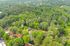 Aerial view of lush green wooded area with scattered houses and roads, offering a serene and peaceful living environment.