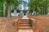 Charming apartment building nestled among tall trees with a welcoming brick pathway leading to the entrance.