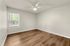 Bright, airy room with sleek wood flooring and a modern ceiling fan, perfect for customization and comfort.