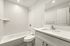 Bright and modern bathroom featuring sleek white tiles, a spacious bathtub, and elegant vanity with ample counter space.