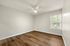 Bright, spacious bedroom with modern ceiling fan, large window, and elegant wood flooring.