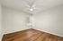 Bright, spacious bedroom with elegant wood flooring, modern ceiling fan, and a window for natural light.