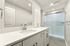 Modern bathroom featuring sleek white cabinetry, elegant chrome fixtures, and a spacious walk-in shower with glass doors.