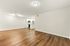 Bright, spacious living area with elegant hardwood flooring, modern recessed lighting, and an open-concept kitchen featuring sleek white cabinets and stainless steel appliances.