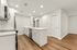 Modern kitchen with sleek white cabinetry, elegant island, stainless steel appliances, and chic wood flooring.