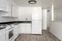 updated kitchen with white cabinets, black countertops, and vinyl plank flooring