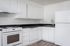 updated kitchen with white cabinets, black countertops, and vinyl plank flooring