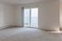 Bright and spacious living room with plush carpet and large sliding glass doors leading to a serene balcony.