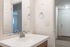 Bright and modern bathroom with a sleek white countertop, elegant chrome faucet, and a large mirror reflecting a welcoming entryway.