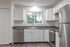 Modern kitchen with sleek stainless steel appliances, white cabinetry, and large window overlooking lush greenery.
