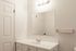 Bright and modern bathroom featuring a sleek white countertop, large mirror, and elegant lighting.