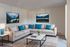 Inviting living room featuring a cozy sectional sofa with vibrant blue pillows, elegant coffee table, and tranquil nature art adorning the walls.
