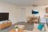 Chic open-concept living space with modern decor, featuring a cozy dining area, stylish wooden floors, and a contemporary wall-mounted TV.