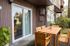 Charming apartment patio with sleek wooden furniture, surrounded by lush greenery for a serene outdoor retreat.