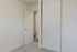 Bright bedroom with plush carpeting, sliding closet doors, and an open door revealing a modern hallway.