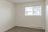 Bright and inviting bedroom with plush carpet flooring and large window providing natural light for a cozy atmosphere.