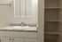 Elegant bathroom with sleek granite countertop, modern sink, and built-in shelving for ample storage.