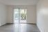 Bright and airy living space with sleek wooden flooring, large sliding glass door, and a view of lush greenery.