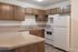 Inviting kitchen showcasing sleek countertops, warm wooden cabinetry, and modern appliances including a white refrigerator and stove.