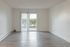 Bright living room with expansive hardwood floors and large sliding glass doors leading to a garden view, offering ample natural light.
