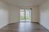 Bright and spacious living room with elegant hardwood floors and large sliding glass doors opening to a lush, green view.