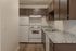 Charming kitchen with elegant granite countertops, modern white appliances, and sleek dark cabinetry.