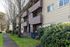 Charming multi-story apartment building with quaint balconies and lush green surroundings, perfect for nature lovers.