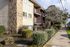 Charming apartment building with stone accents and private balconies, surrounded by lush landscaping and a welcoming sidewalk.