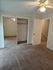 Bright bedroom with plush carpet, mirrored closet doors, and modern ceiling fan, offering a cozy and inviting space.