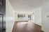 Bright, spacious living area with wood flooring and large windows leading to a balcony, offering a modern and airy ambiance.