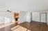 Bright and airy open-concept apartment featuring sleek wooden floors, a stylish ceiling fan, and a modern kitchen with warm wooden cabinets.