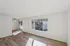 Bright and spacious living area featuring elegant wood flooring, large windows with abundant natural light, and a ceiling fan for modern comfort.