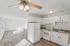 Bright and inviting kitchen with elegant white cabinetry, modern appliances, and chic lighting, seamlessly flowing into a spacious open living area with large windows illuminating the space.