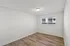 Bright and spacious bedroom with fresh white walls and sleek wood flooring, featuring large windows for ample natural light.