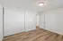 Bright and airy bedroom with elegant hardwood floors, ample closet space, and modern light fixture, offering a tranquil and inviting atmosphere.