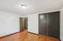 Bright empty room with sleek wooden floors and a modern sliding closet door, ideal for personal customization.