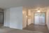 Bright and modern living area with fresh carpet, compact kitchenette, and sliding glass doors opening to a serene outdoor view.