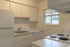 Bright and compact kitchen with sleek white cabinetry, modern appliances, and a cozy window view.
