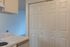 Bright kitchen corner with elegant marble countertops and sleek double-door pantry, leading to a cozy living area.