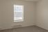 Bright and inviting bedroom with neutral walls, plush carpet, and a window welcoming natural light.