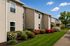 Charming apartment building exterior with lush landscaping and vibrant flowers under a bright blue sky.