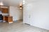 Modern apartment interior featuring a bright open-plan kitchen with wooden cabinets and stainless steel appliances, complemented by elegant light wood flooring and ceiling fan lighting.