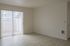 Bright apartment room with elegant light wood flooring and large sliding glass doors leading to a private balcony.